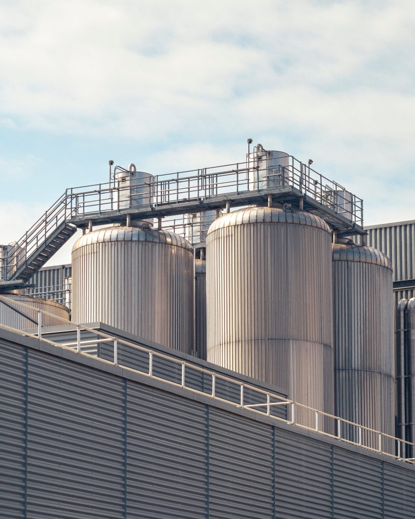 pexels photo 18568174 18568174 A view of metal storage tanks outside an industrial facility under a partly cloudy sky.